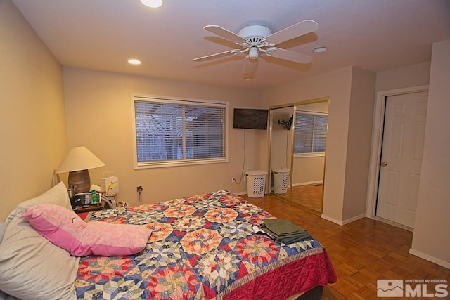 bedroom with parquet floors, ceiling fan, and a closet