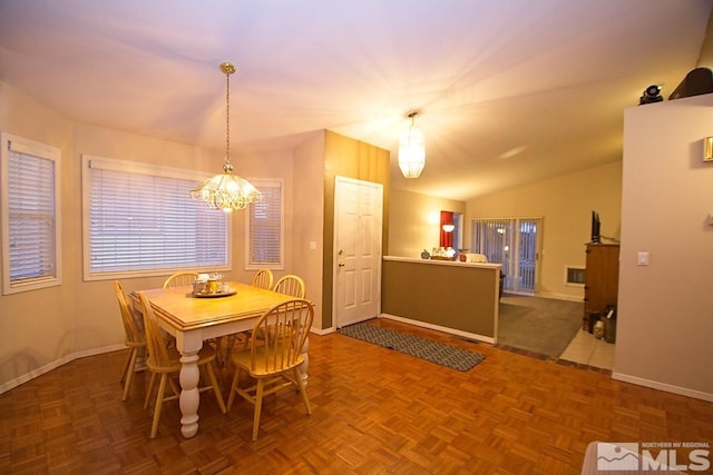 dining space with lofted ceiling, dark parquet floors, and an inviting chandelier