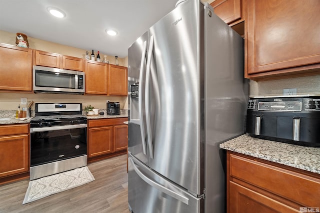 kitchen featuring light stone countertops, stainless steel appliances, and light hardwood / wood-style floors