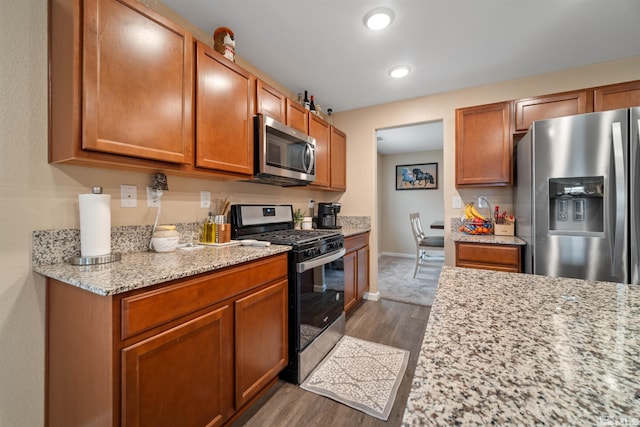 kitchen featuring appliances with stainless steel finishes, light stone counters, and dark wood-type flooring