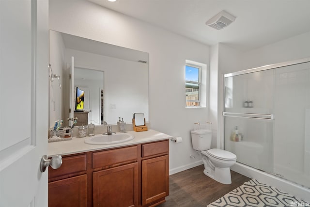 bathroom featuring hardwood / wood-style floors, vanity, a shower with shower door, and toilet