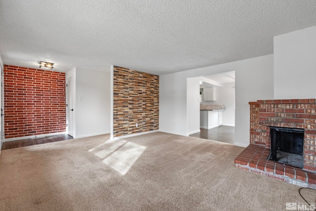 unfurnished living room with a brick fireplace, a textured ceiling, dark carpet, and brick wall