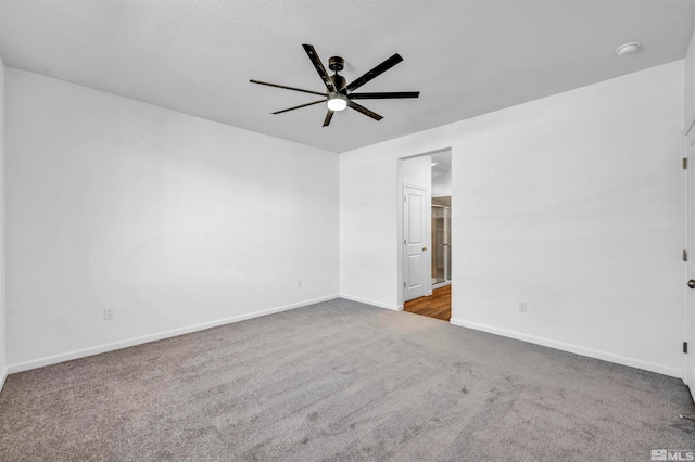 empty room with ceiling fan and dark carpet