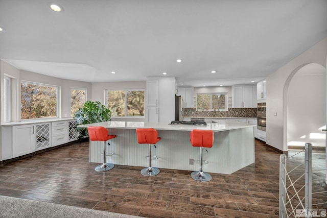 kitchen featuring a breakfast bar, a center island, dark hardwood / wood-style floors, and white cabinetry