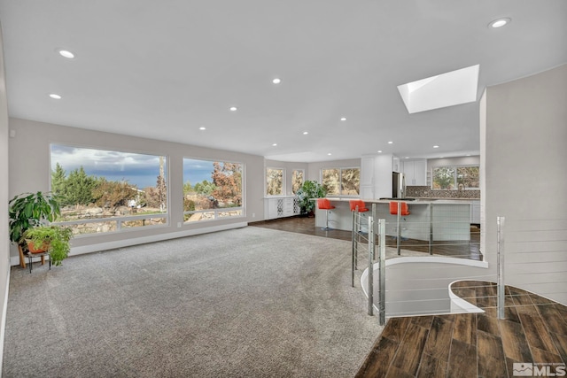 unfurnished living room featuring hardwood / wood-style floors and a skylight