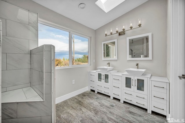 bathroom with hardwood / wood-style floors, vanity, vaulted ceiling with skylight, and tiled shower