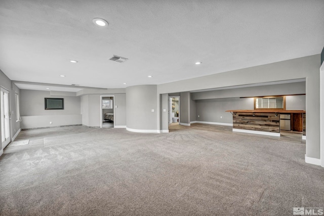 unfurnished living room featuring a textured ceiling and light carpet