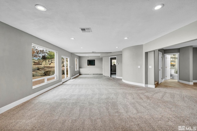 unfurnished living room featuring light carpet and a textured ceiling