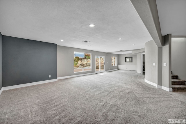 unfurnished living room with light carpet and a textured ceiling