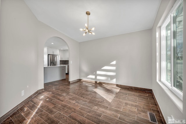 empty room featuring dark hardwood / wood-style floors, lofted ceiling, and an inviting chandelier