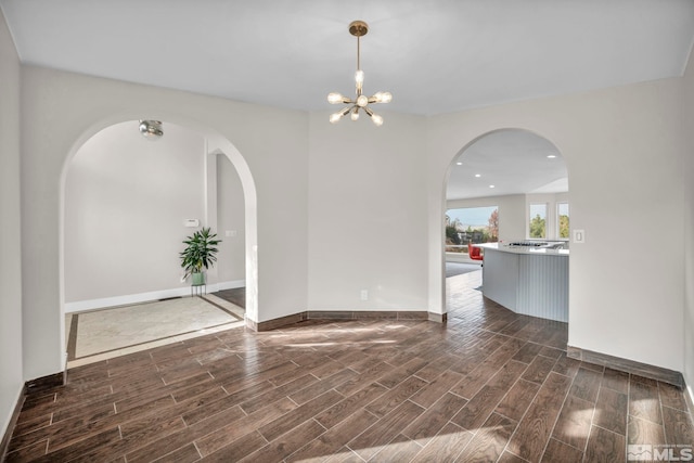 empty room with a chandelier and dark hardwood / wood-style floors