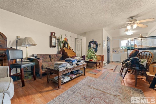 living room featuring wood-type flooring, a textured ceiling, and ceiling fan