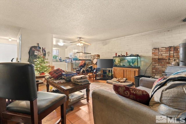 living room featuring wood-type flooring, a textured ceiling, ceiling fan, and brick wall