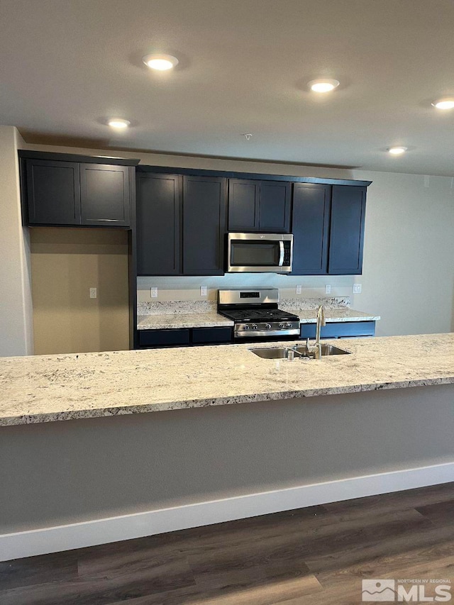 kitchen featuring light stone countertops, appliances with stainless steel finishes, dark hardwood / wood-style flooring, and sink