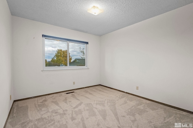 carpeted empty room featuring a textured ceiling