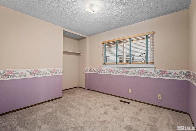 unfurnished bedroom featuring light carpet, a closet, and a textured ceiling