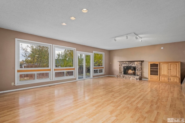 unfurnished living room with a healthy amount of sunlight, light hardwood / wood-style floors, and a textured ceiling