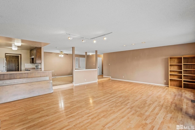 unfurnished living room featuring a textured ceiling and light hardwood / wood-style floors