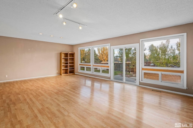 unfurnished room featuring light wood-type flooring and a textured ceiling