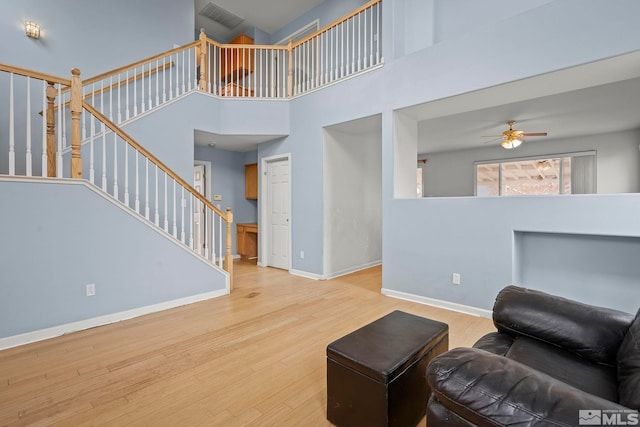 living room with ceiling fan, hardwood / wood-style floors, and a high ceiling