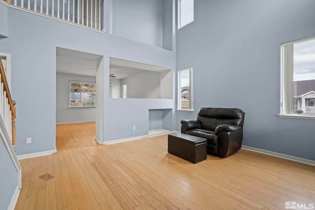 living area with a towering ceiling and light hardwood / wood-style floors