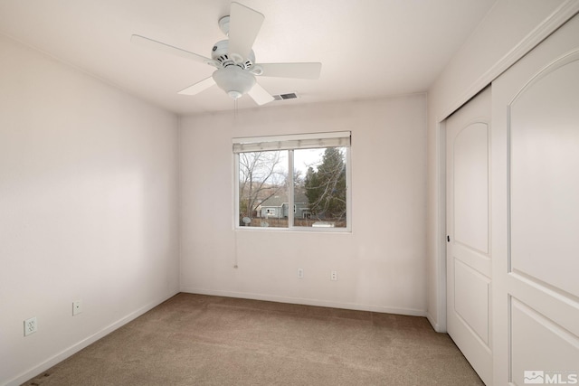 unfurnished bedroom featuring a closet, light colored carpet, and ceiling fan