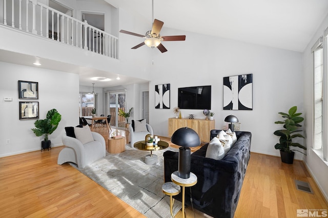 living room with hardwood / wood-style flooring, ceiling fan, and high vaulted ceiling