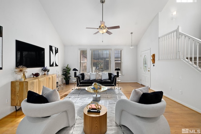 living room with ceiling fan, light wood-type flooring, and high vaulted ceiling