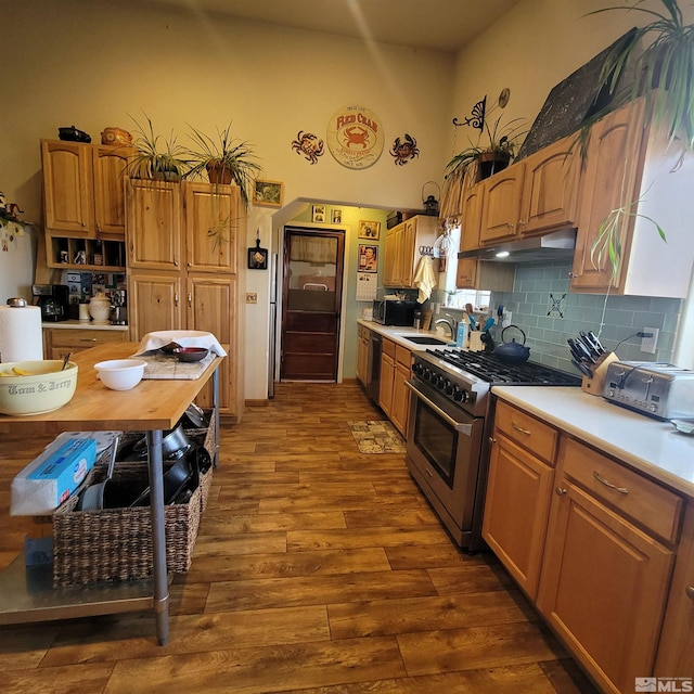 kitchen with sink, stainless steel range, black dishwasher, tasteful backsplash, and hardwood / wood-style flooring