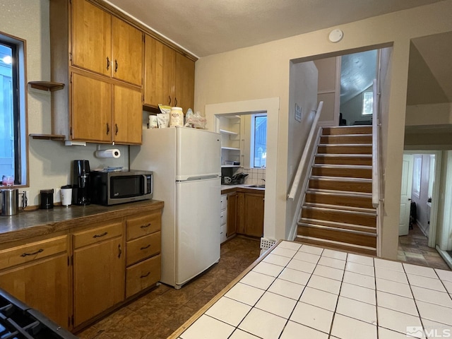 kitchen with tasteful backsplash, light tile patterned floors, lofted ceiling, and white refrigerator