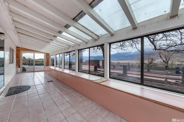 unfurnished sunroom with a mountain view and lofted ceiling with beams