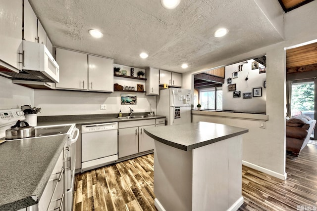 kitchen featuring a textured ceiling, a center island, hardwood / wood-style floors, and white appliances