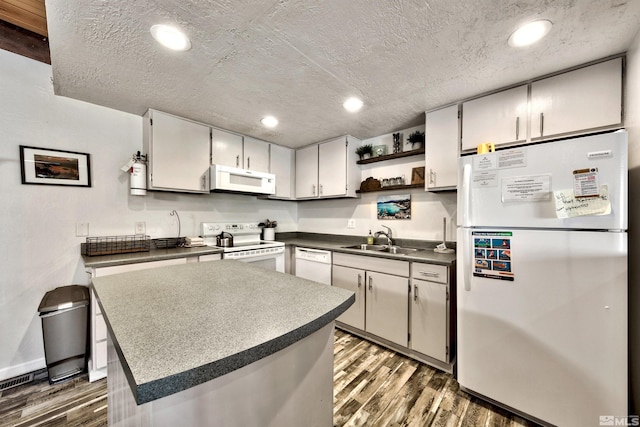 kitchen featuring a textured ceiling, white appliances, dark wood-type flooring, and sink