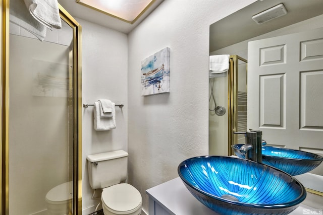 bathroom featuring sink, a shower with shower door, and toilet