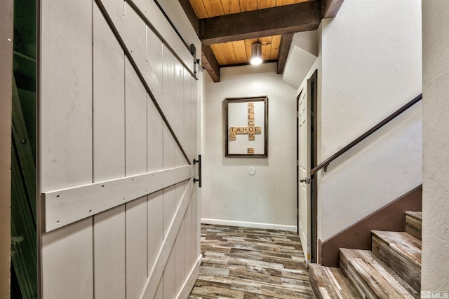 staircase featuring beam ceiling, a barn door, wooden ceiling, and hardwood / wood-style flooring