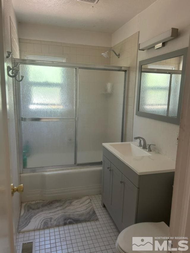 full bathroom featuring toilet, vanity, tile patterned floors, and bath / shower combo with glass door