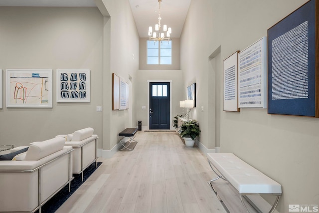 foyer with a chandelier, a high ceiling, and light wood-type flooring