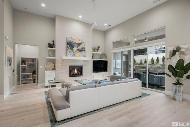 living room featuring a towering ceiling, light wood-type flooring, and ceiling fan