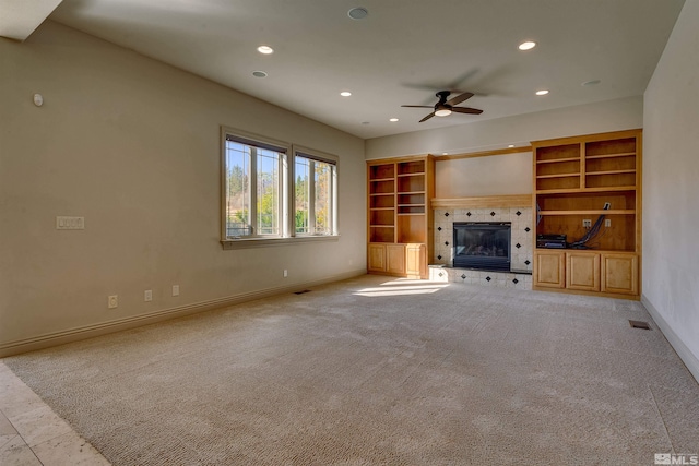 unfurnished living room with ceiling fan, light carpet, and a tile fireplace