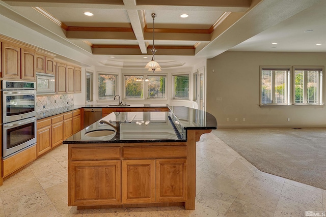 kitchen with appliances with stainless steel finishes, dark stone counters, sink, pendant lighting, and beam ceiling