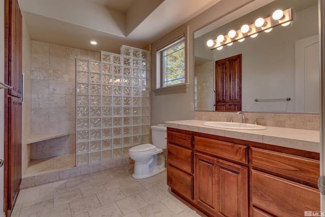 bathroom with vanity, toilet, tiled shower, and tile walls