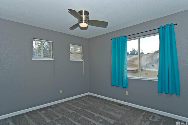 spare room with dark colored carpet and ceiling fan