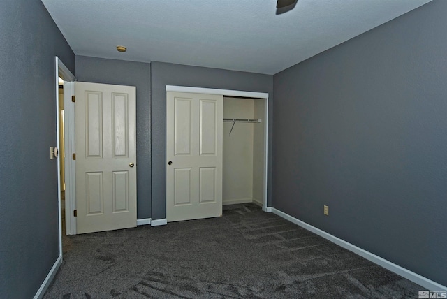 unfurnished bedroom featuring dark colored carpet, ceiling fan, and a closet