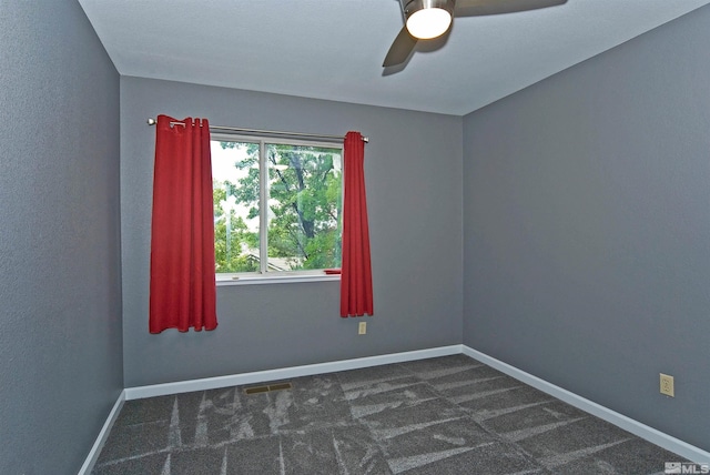 empty room with ceiling fan and dark carpet