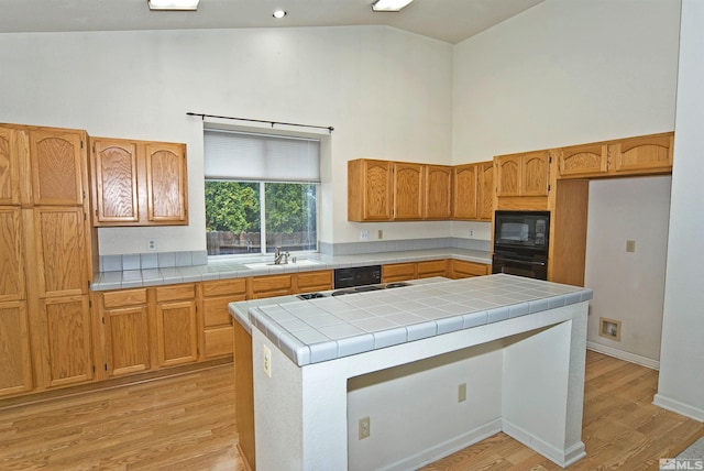 kitchen featuring sink, high vaulted ceiling, tile countertops, black appliances, and light wood-type flooring