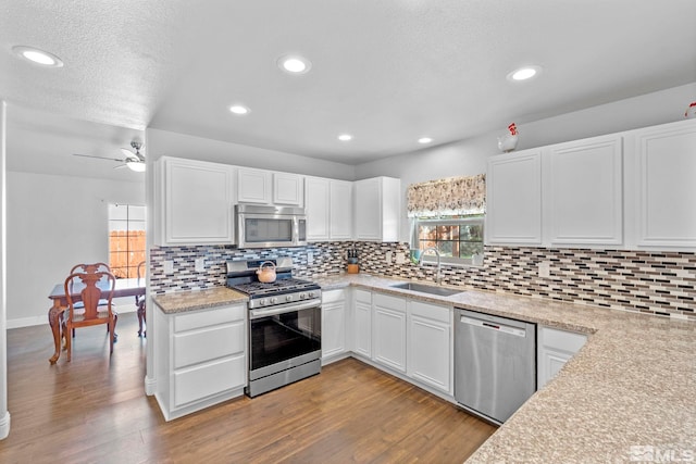 kitchen featuring white cabinetry, sink, tasteful backsplash, appliances with stainless steel finishes, and light wood-type flooring