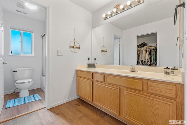 full bathroom with toilet, vanity, enclosed tub / shower combo, and hardwood / wood-style flooring