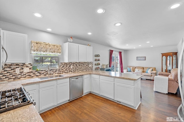 kitchen with white cabinets, sink, hardwood / wood-style flooring, appliances with stainless steel finishes, and kitchen peninsula