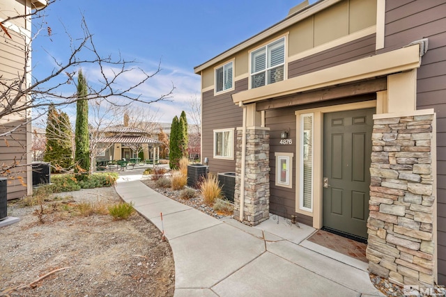 entrance to property featuring stone siding and central air condition unit