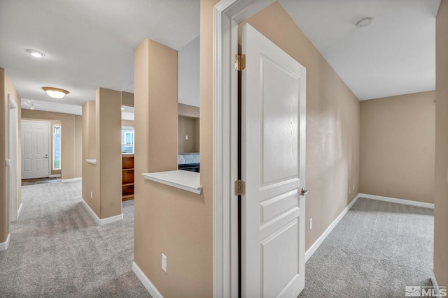 hallway featuring carpet flooring and baseboards